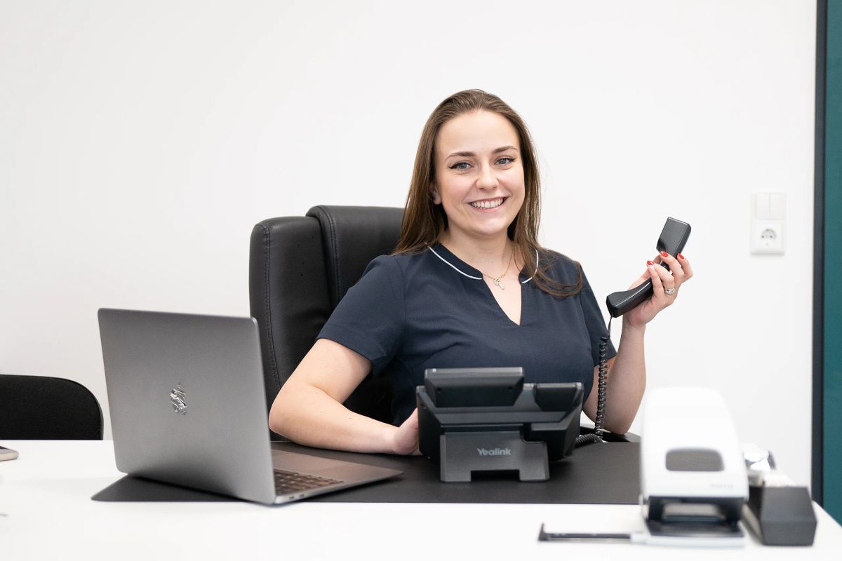 Frau Stankay am Schreibtisch im Büro von Vollwinkel, den Telefonhörer in der Hand